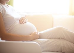 Pregnancy. Happy pregnant woman lying in bed and touching her belly at home.